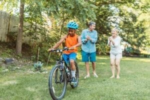 A Happy Couple Cheering For Their Son Riding A Bike