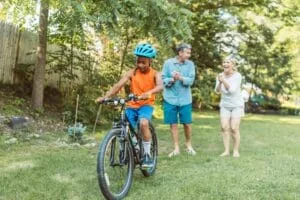 A Happy Couple Cheering For Their Son Riding A Bike